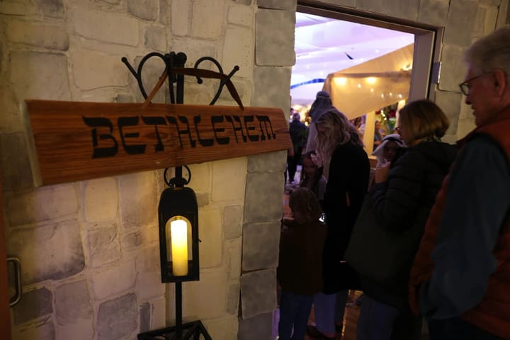 A lantern beside the wooden Bethlehem sign at the gate.
