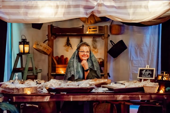 A volunteer smiling behind a marketplace stall of bread.