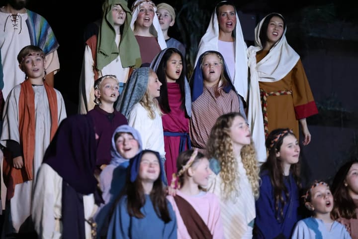 A group of young volunteers in biblical costumes on the nativity stage.